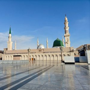 Beautiful view of the Masjid an-Nabawi in Medina with clear blue skies, capturing its iconic domes and minarets.